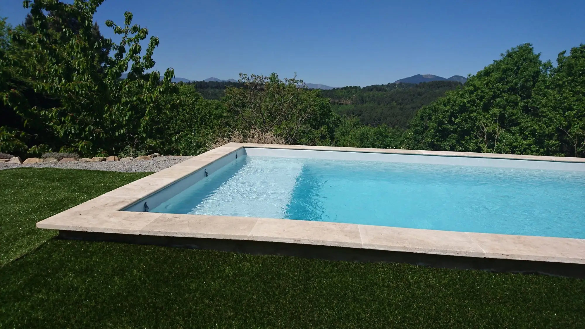 Piscine à margelles claires face aux montagnes à Saint-Julien-du-Serre