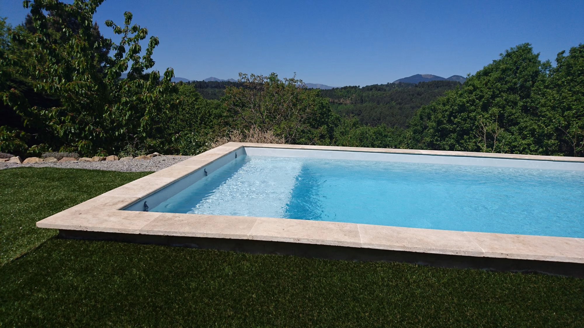 Piscine à margelles claires face aux montagnes à Saint-Julien-du-Serre