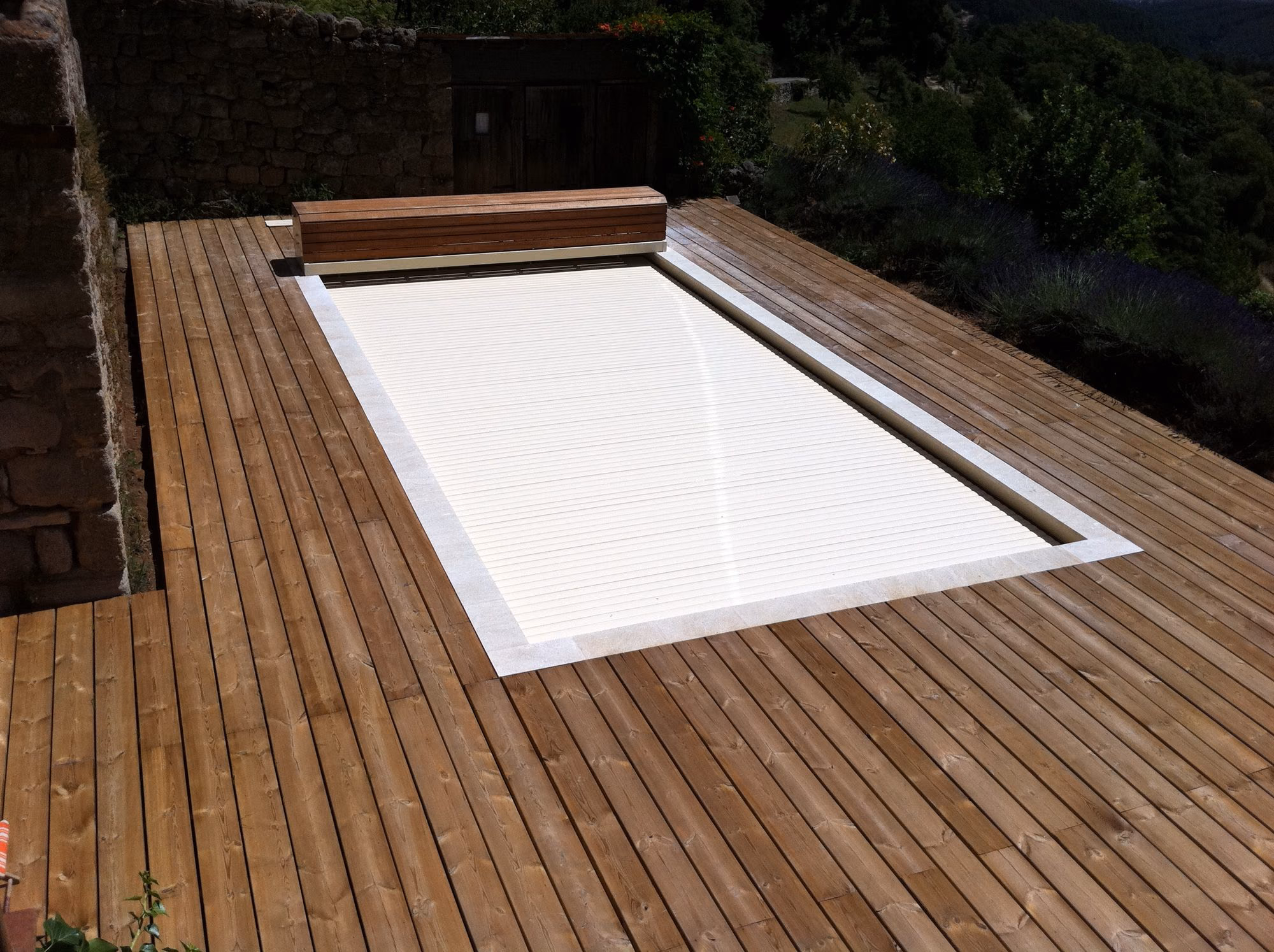 Volet fermé sur une piscine entourée de terrasse en pin à Sanilhac