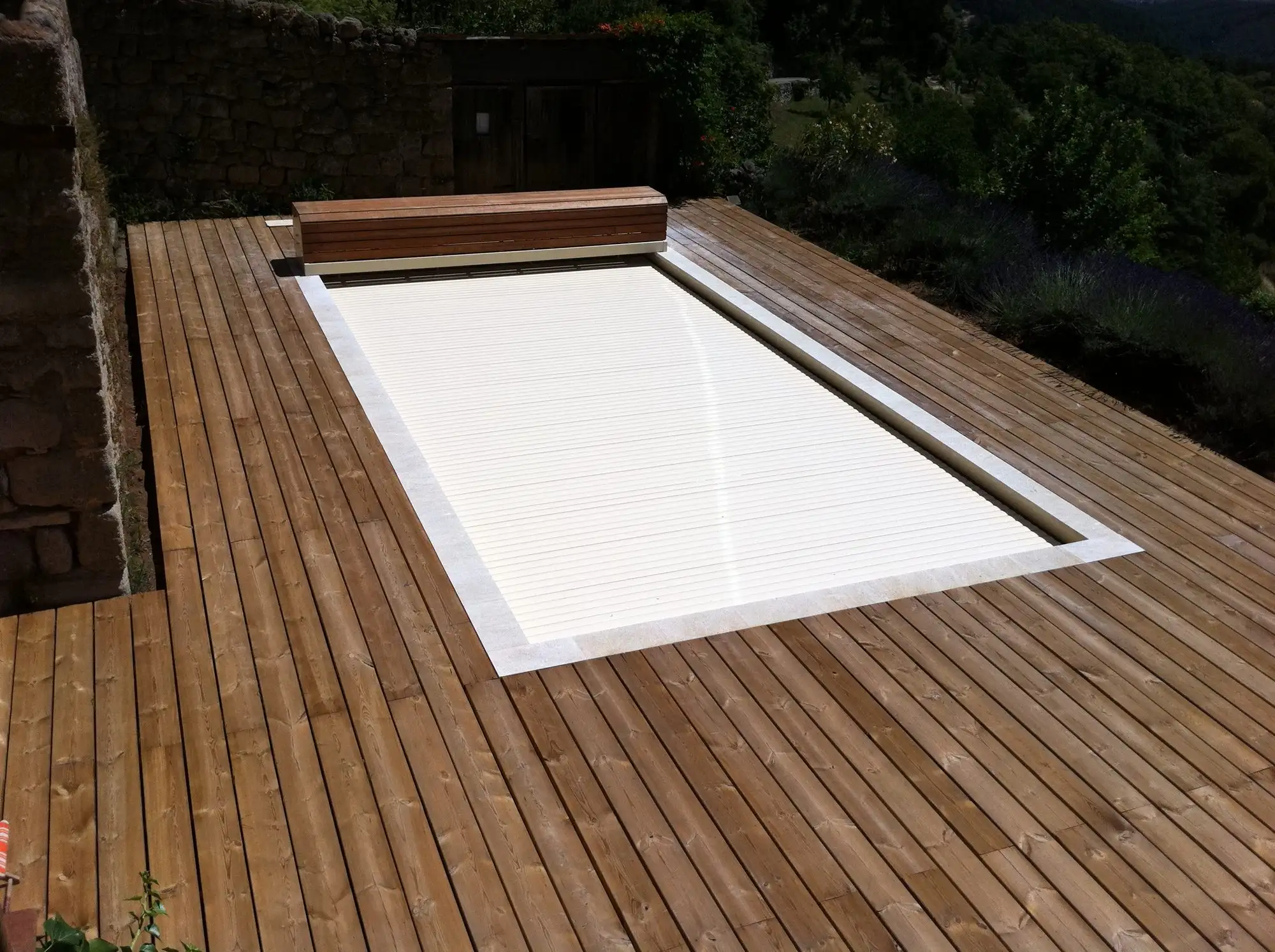 Volet fermé sur une piscine entourée de terrasse en pin à Sanilhac