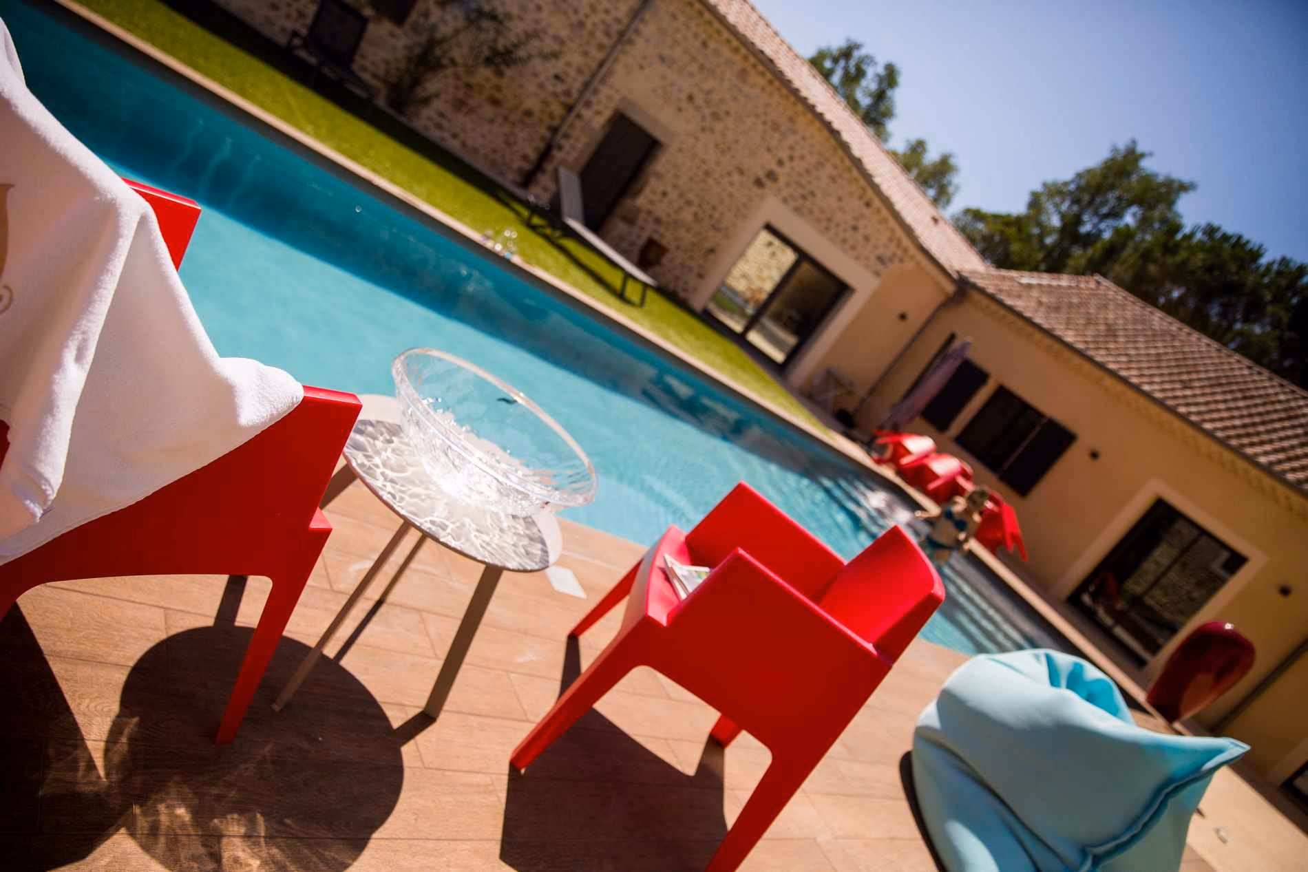 Plage effet bois et fauteuils rouges au bord du bassin, cour en pierre de Saint-Didier-sous-Aubenas