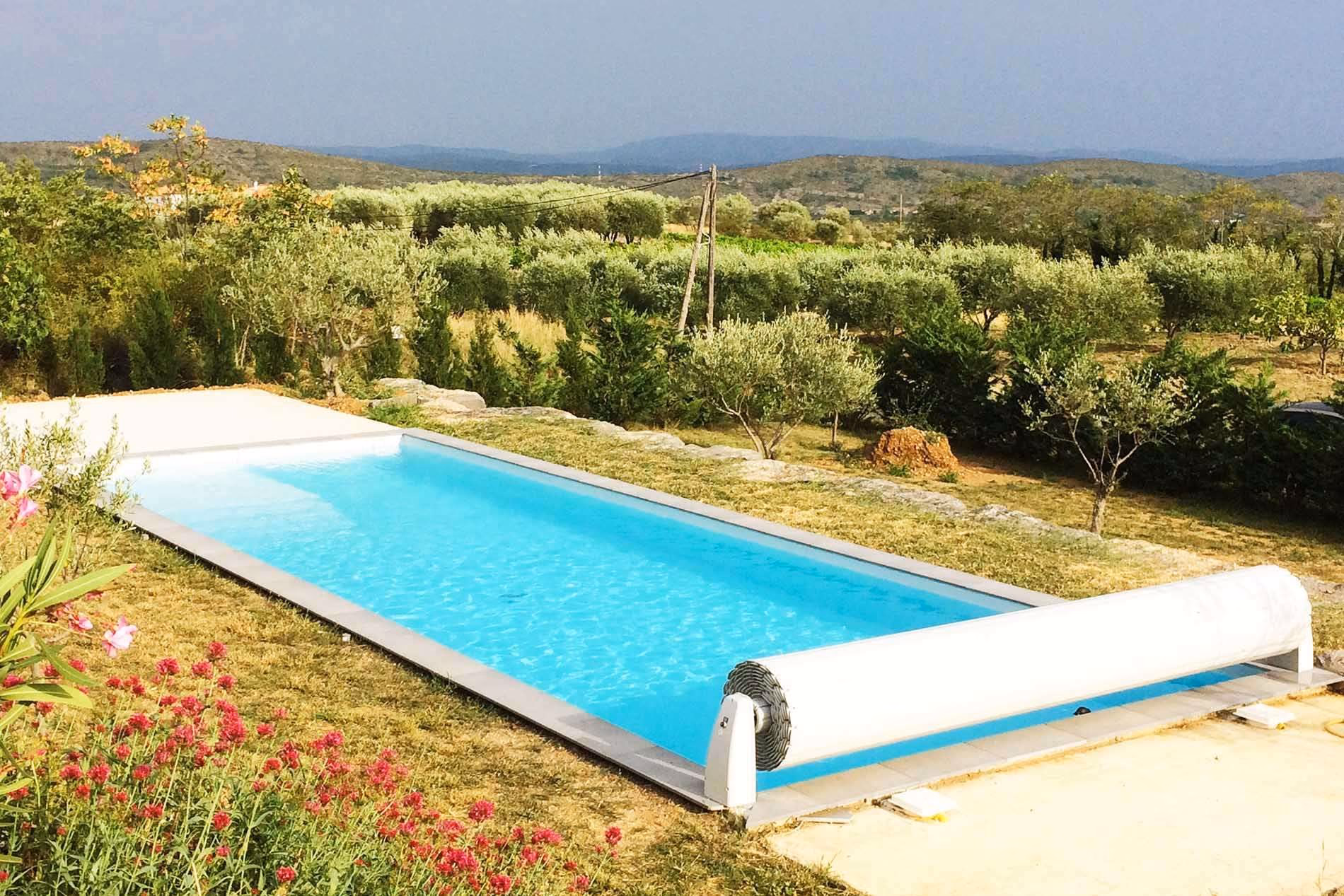 Piscine fermée par son volet hors sol, massif fleuri et vue sur les collines, à Largentière