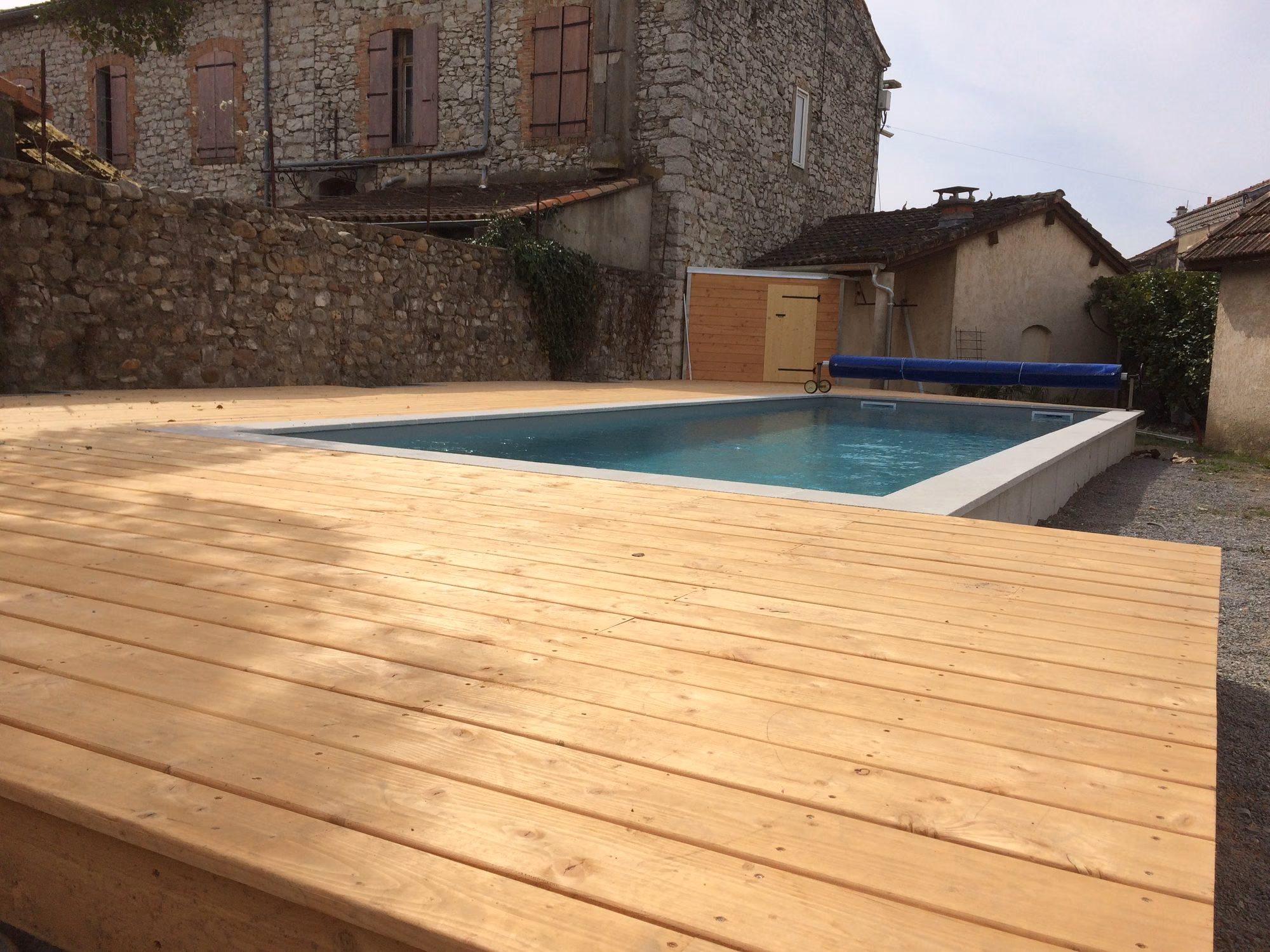 Piscine en eau et terrasse bois entre maisons en pierre à Ruoms