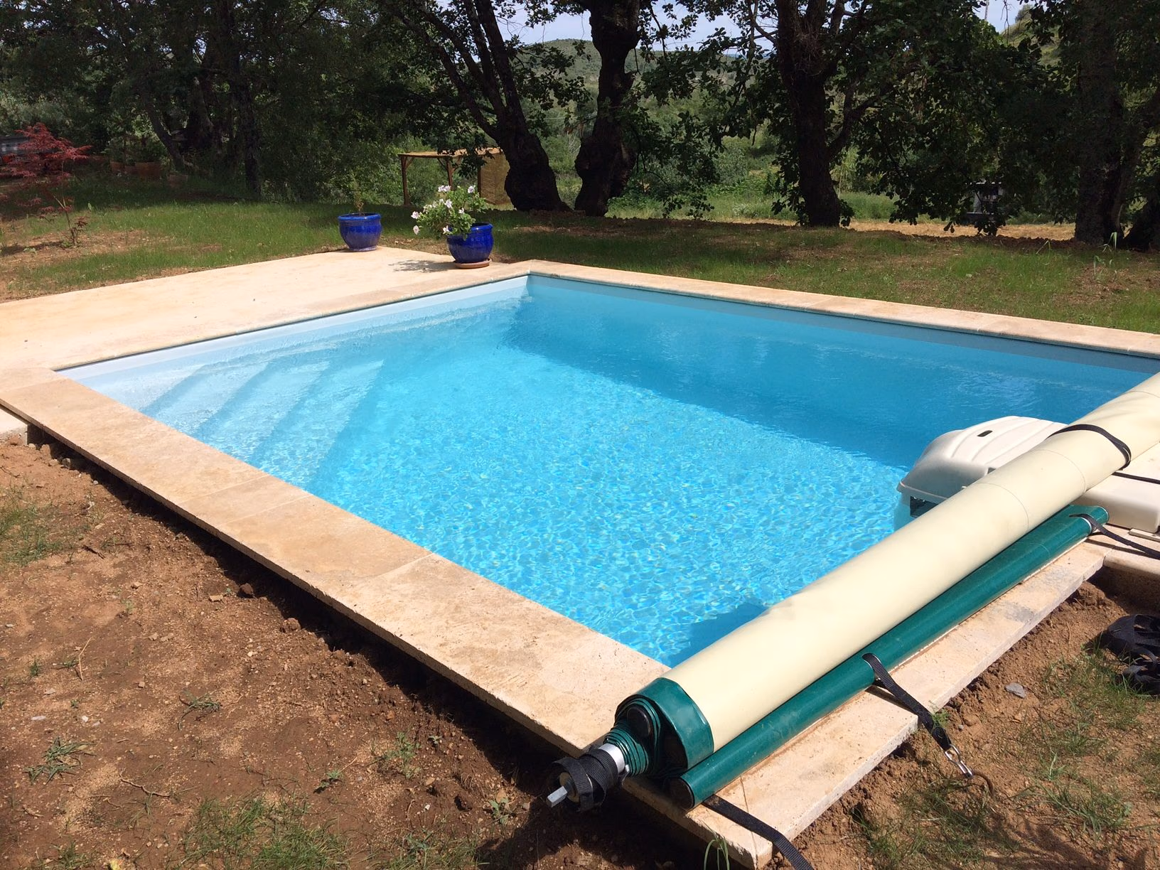 Piscine à margelles claires dans un jardin à Vinezac