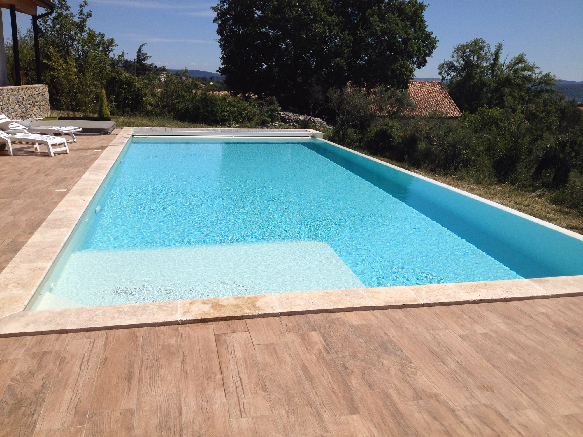 Piscine à débordement avec plage immergée et carrelage effet bois à Aubenas