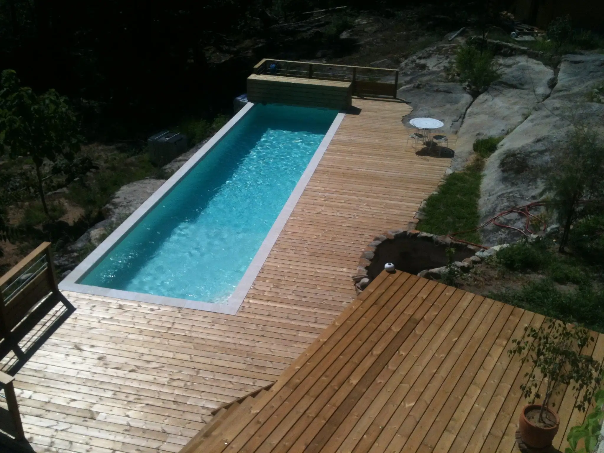 Couloir de nage en béton bordé d'une terrasse en bois entre les rochers, en Ardèche