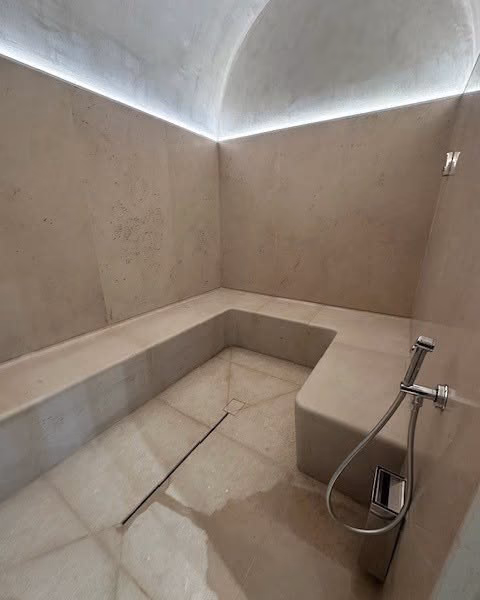 Hammam voûté en pierre claire, banquettes et éclairage indirect
