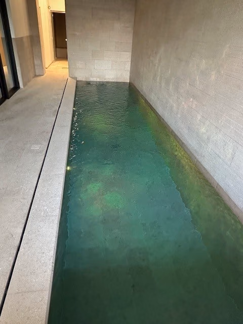 Piscine intérieure étroite et allongée, murs et plage en pierre claire
