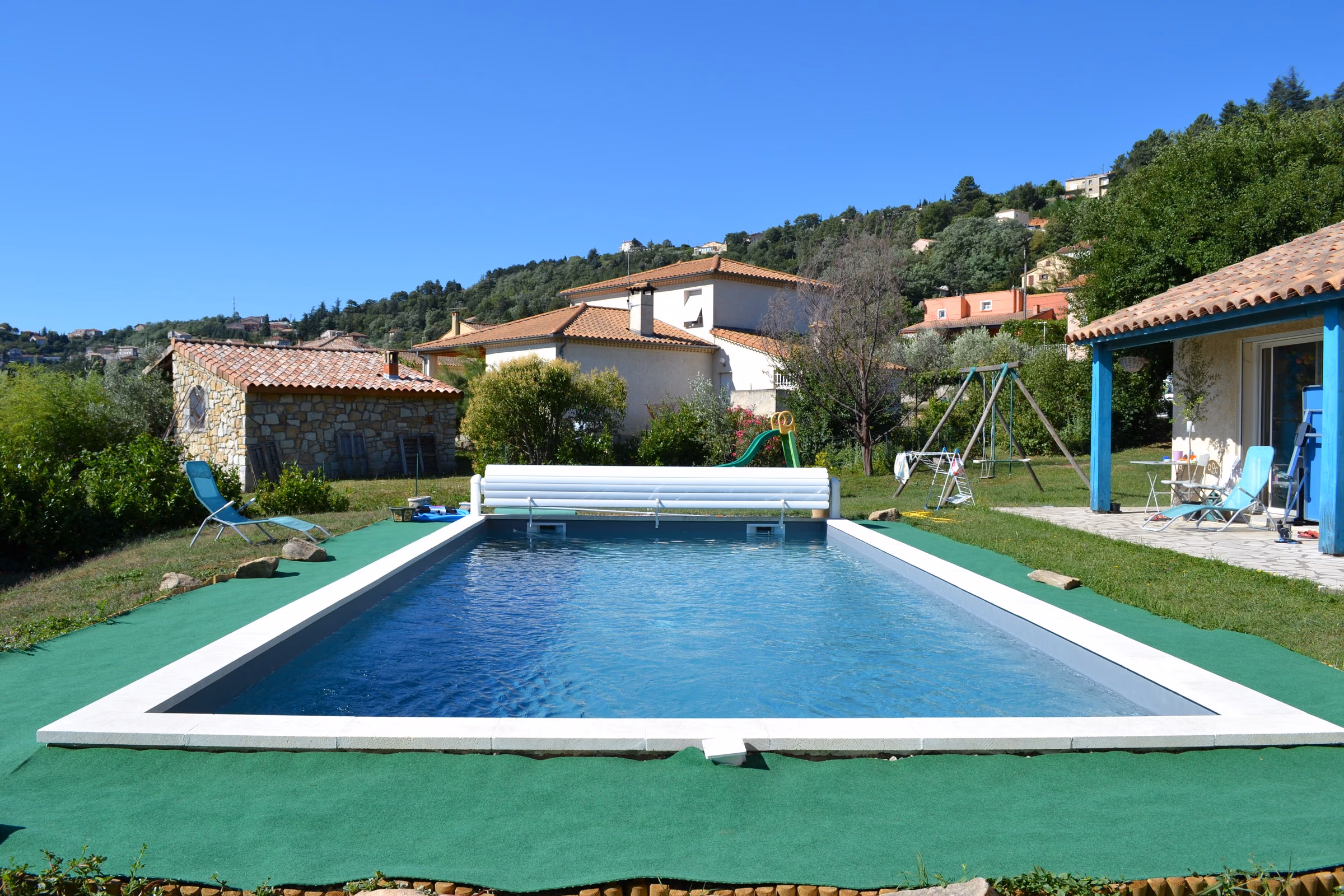 Piscine en béton et terrasse en bois face aux collines ardéchoises