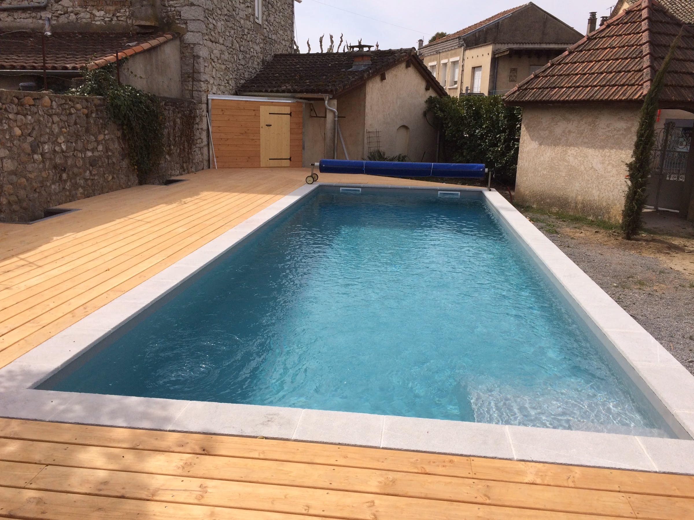 Piscine en béton livrée, terrasse en pin, dans une cour de village à Ruoms