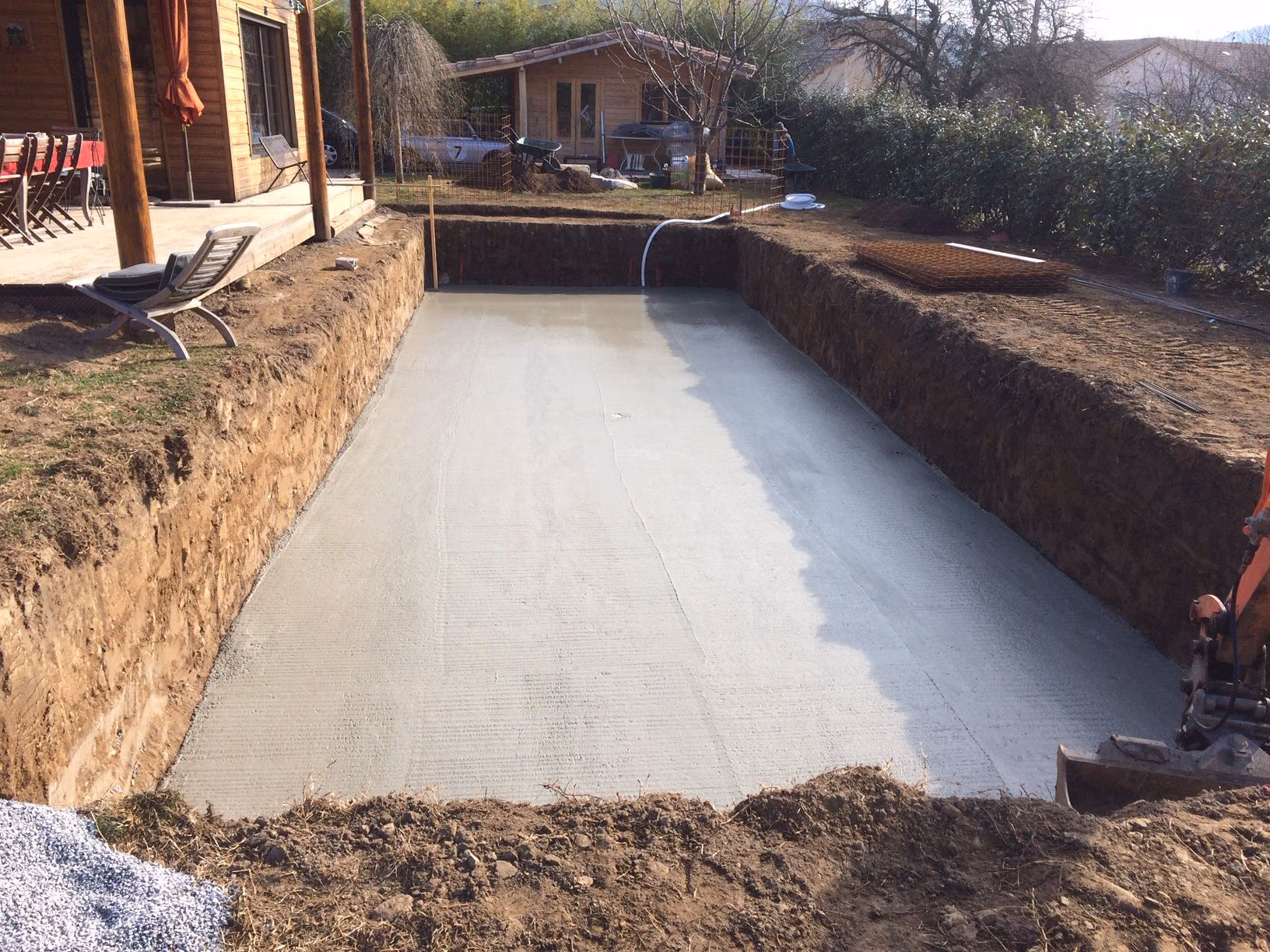 Fouille terrassée et radier coulé au fond, devant la maison, chantier en Ardèche
