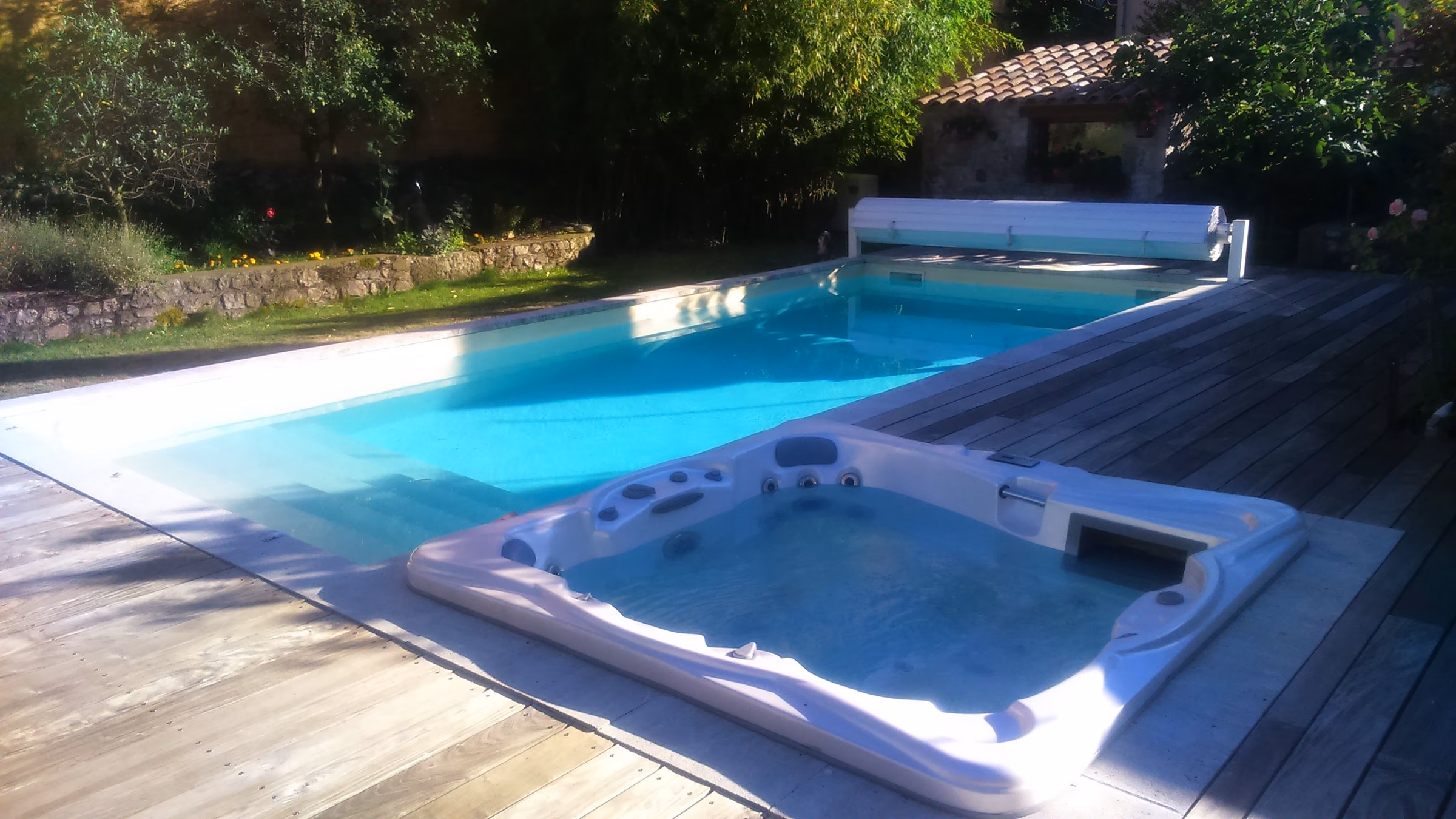 Spa encastré dans une terrasse en bois, au bord d’une piscine